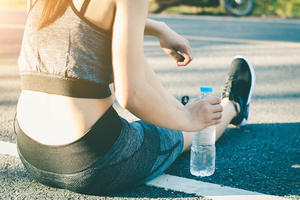 Young women stops drink water resting after running.