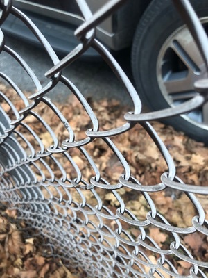 angled view of a car seen through a chain linked fence