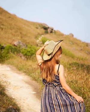 Girl with straw hat in the road fields
