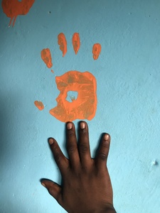 Child hand near an orange print hand