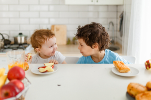 Happy children breakfast with fresh fruits in bright kitchen
