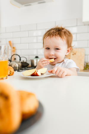 Happy kid breakfast with fresh fruits in bright kitchen