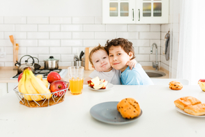 Happy children breakfast with fresh fruits in bright kitchen