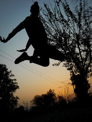 Jumping man silhouettes on sunset background