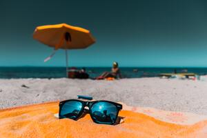 Sunglasses lying on towel on beach