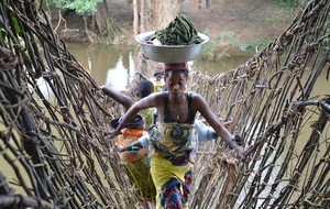 African woman walking with wash over wooden bridge
