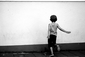 Child dancing in the street in front of a wall