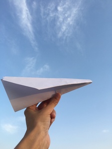 a hand holding airplane made with white paper