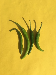 Green chilies on yellow background wallpaper image