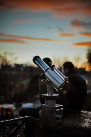 Standing outside with a telescope viewing the starry sky.