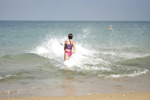 Little girl running into the sea through waves