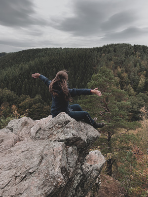 Girl sitting on rock and looking over forest