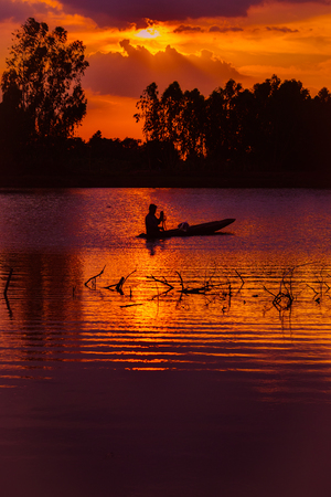 Fisherman in boat on the river during sunset