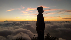Boy standing on top of mountain at sunset