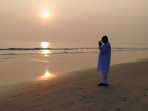 Man worshipping on the beach at sunset