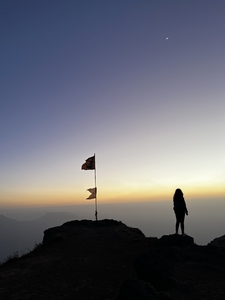 Woman standing on top of mountain at sunset