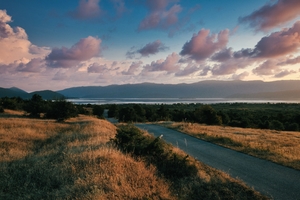 An empty road overlooking a cloudy sunset on Lake Prespa