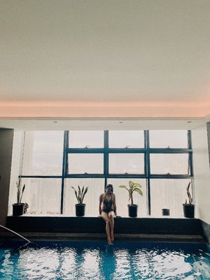 Woman in swimsuit sitting next to indoor pool