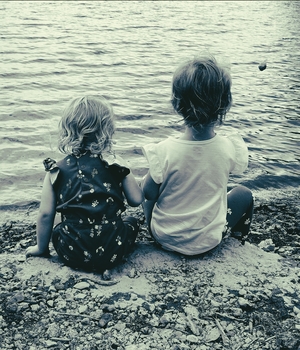 Boy and girlsitting next to each other on the shore