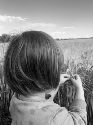 Portrait of a little girl from behind standing  in field black and white