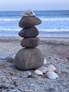 Stack of balanced stones at beach against clear sky