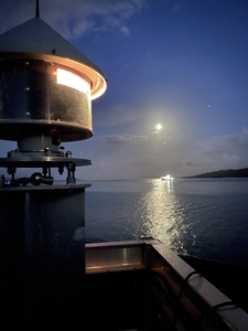 lighthouse flashing with ship and moon