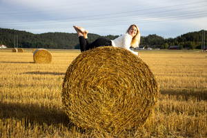 Wom,an lookik at camera and lying on hayball