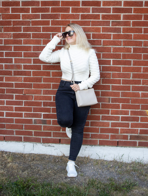 Blonde woman with sunglasses leaning against wall