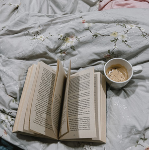 Cup of coffee and book on bed