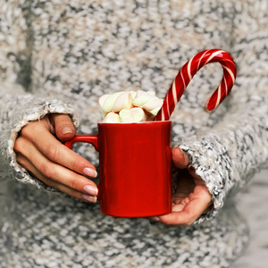 red mug with hot coffee with marshmallows and candy cane